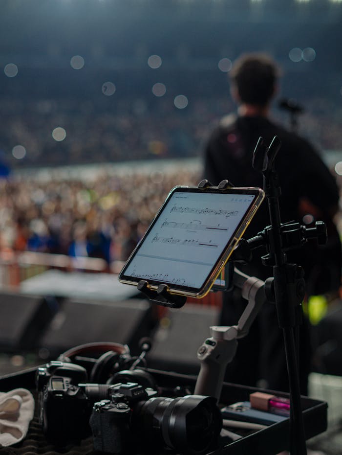 A musician performing on stage with professional photography and music equipment in view.
