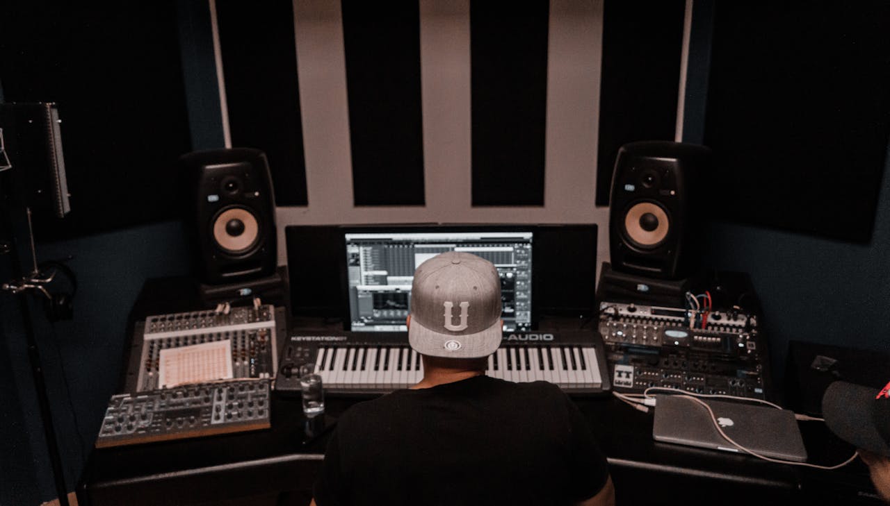 A music producer working in a modern studio with keyboards and monitors. Perfect for music industry visuals.